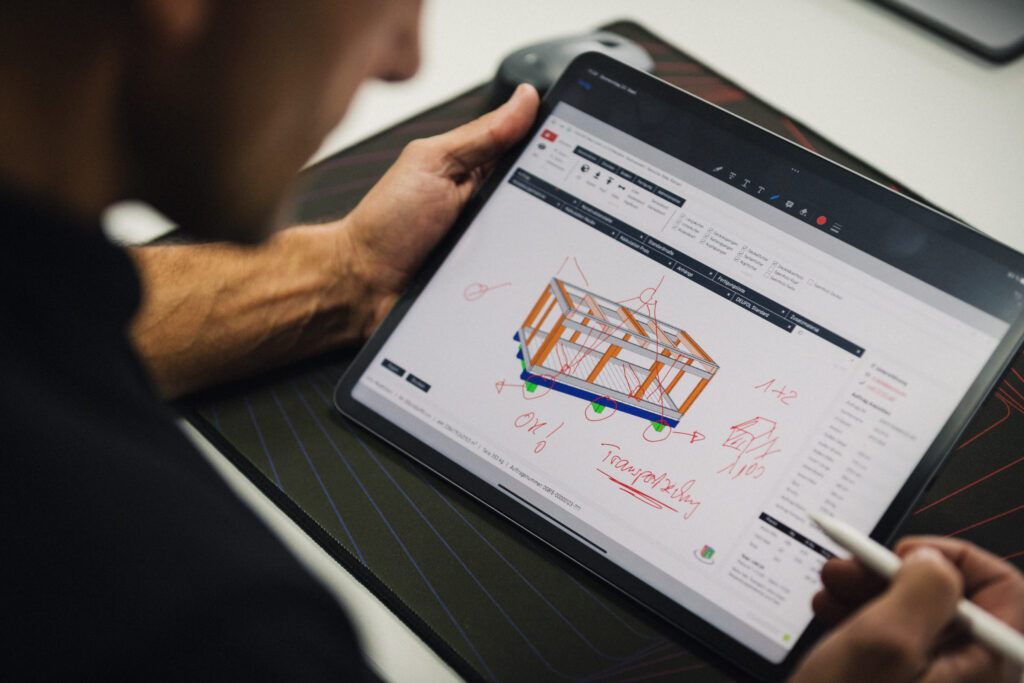 Ein Mann entwirft auf einem Tablet eine Holzverpackung für den Transport.